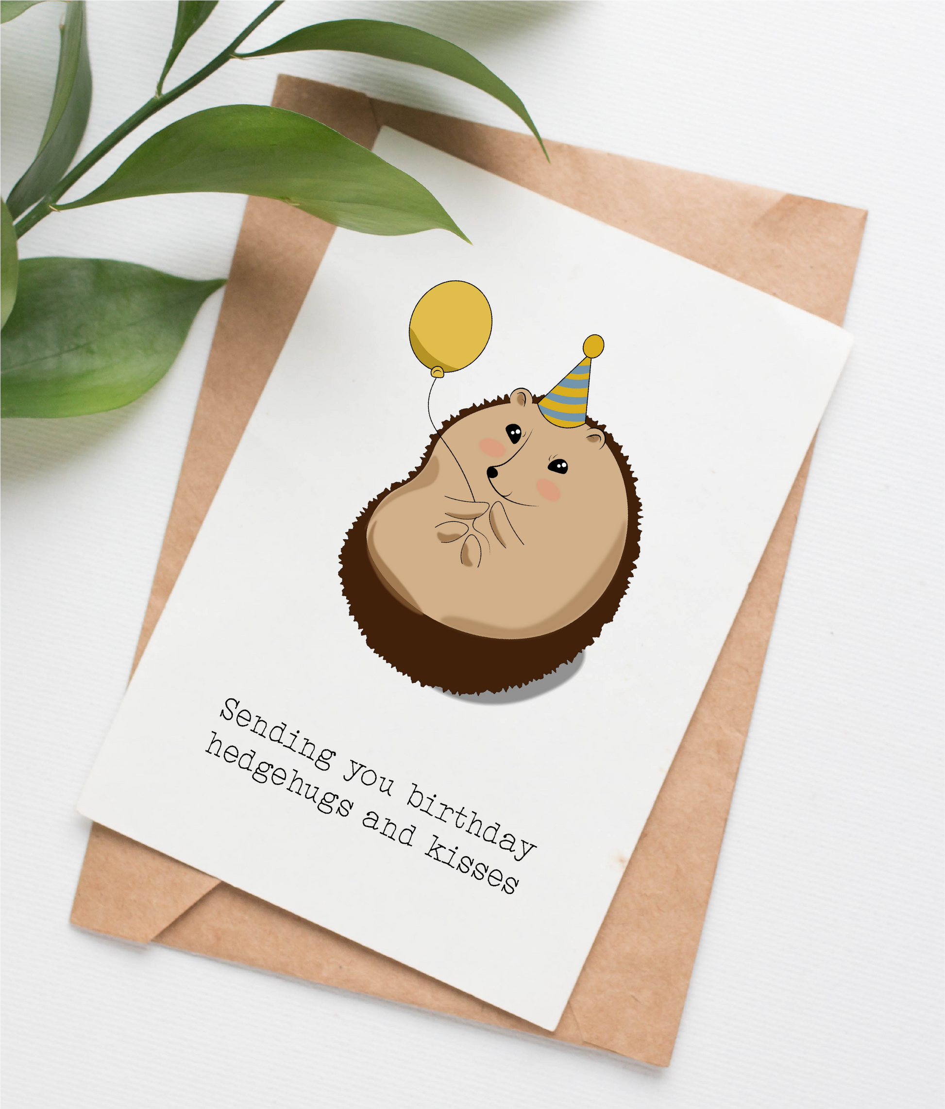 This handmade card is made in Canada. It shows an illustration of a cute hedgehog holding a balloon and wearing a birthday hat. The caption says "Sending you birthday hedgehugs and kisses"