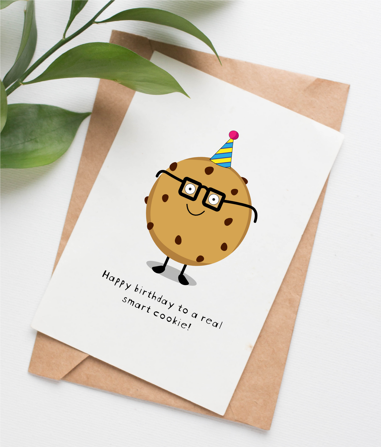This handmade card is made in Canada. It shows an illustration of a smiling chocolate chip cookie wearing glasses and a birthday hat. The caption says "Happy birthday to a real smart cookie!"
